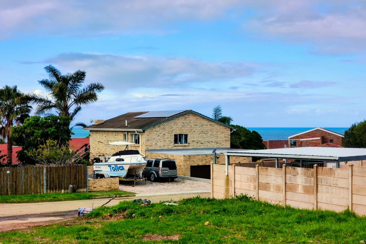 A view of a residential property featuring a brick facade, solar panels, and a paved driveway, situated in a coastal neighborhood.