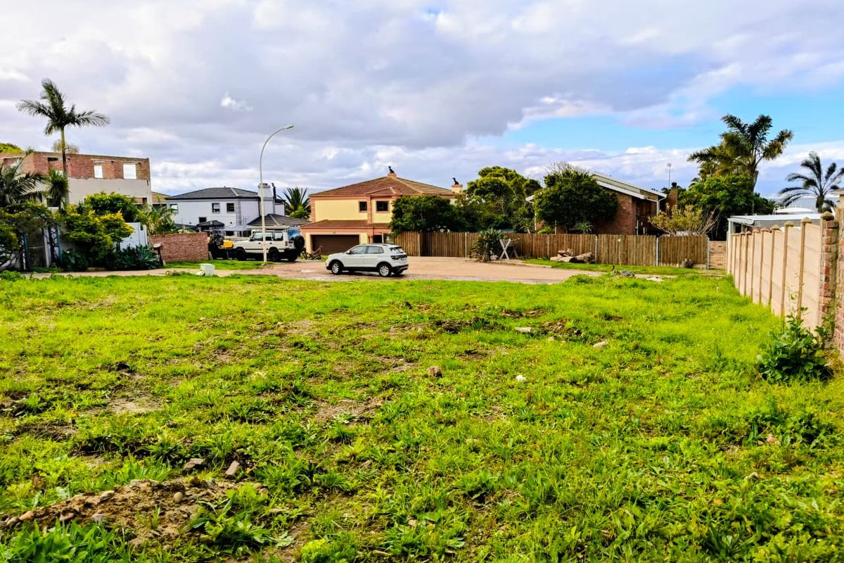 A vacant residential plot featuring established boundary fencing and natural grass cover, situated in a developed suburban neighborhood.