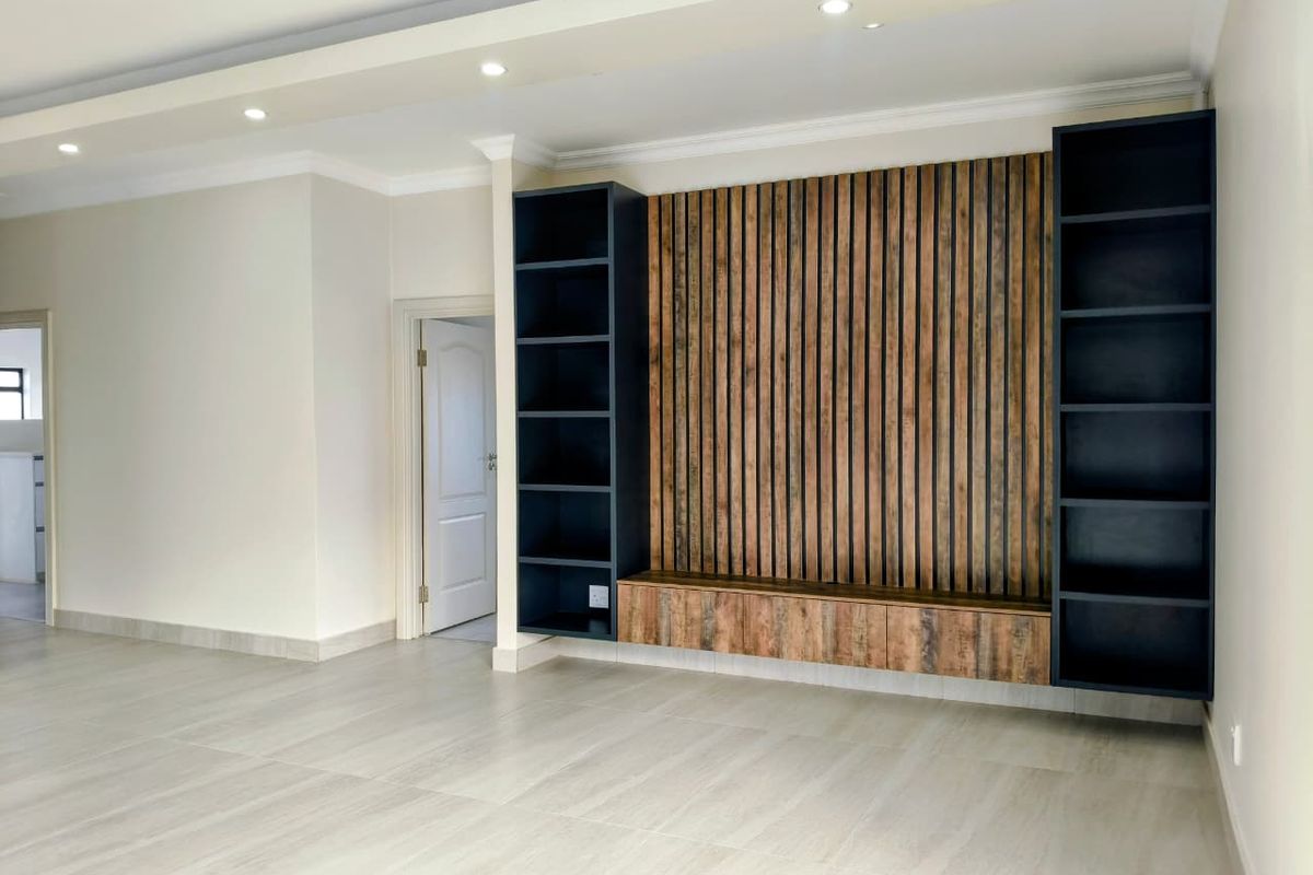 A bright, modern living area featuring a custom timber slat feature wall with integrated shelving and sleek tiled flooring.