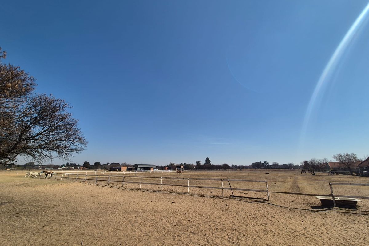 Expansive open paddock area featuring post and rail fencing and a fixed water trough, suitable for equestrian use.