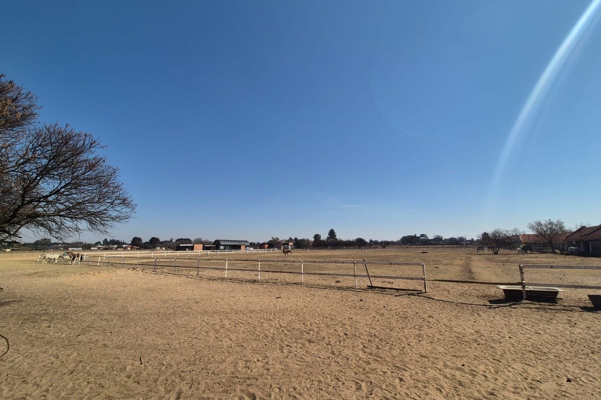 Expansive open paddock area featuring post and rail fencing and a water trough, suitable for equestrian use.