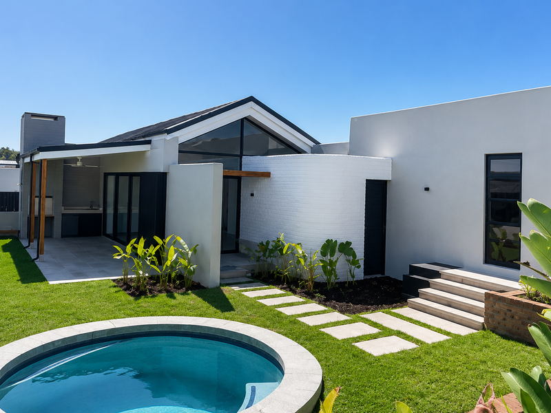 Modern rear exterior featuring a swimming pool, covered patio with built-in braai, and landscaped garden with stone pathways.