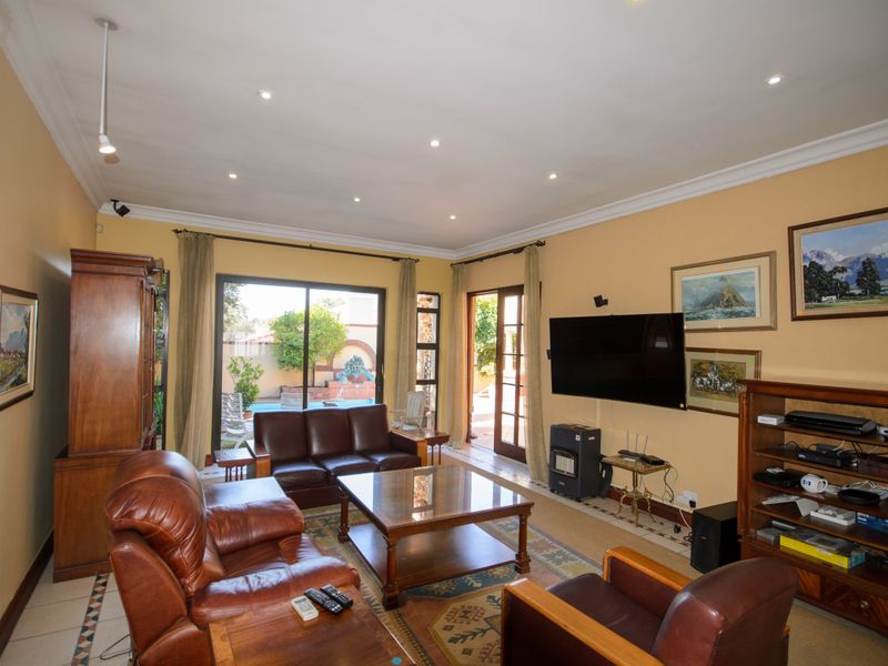 Spacious living room featuring tiled flooring, recessed lighting, and large sliding glass doors providing direct access to the outdoor pool area.