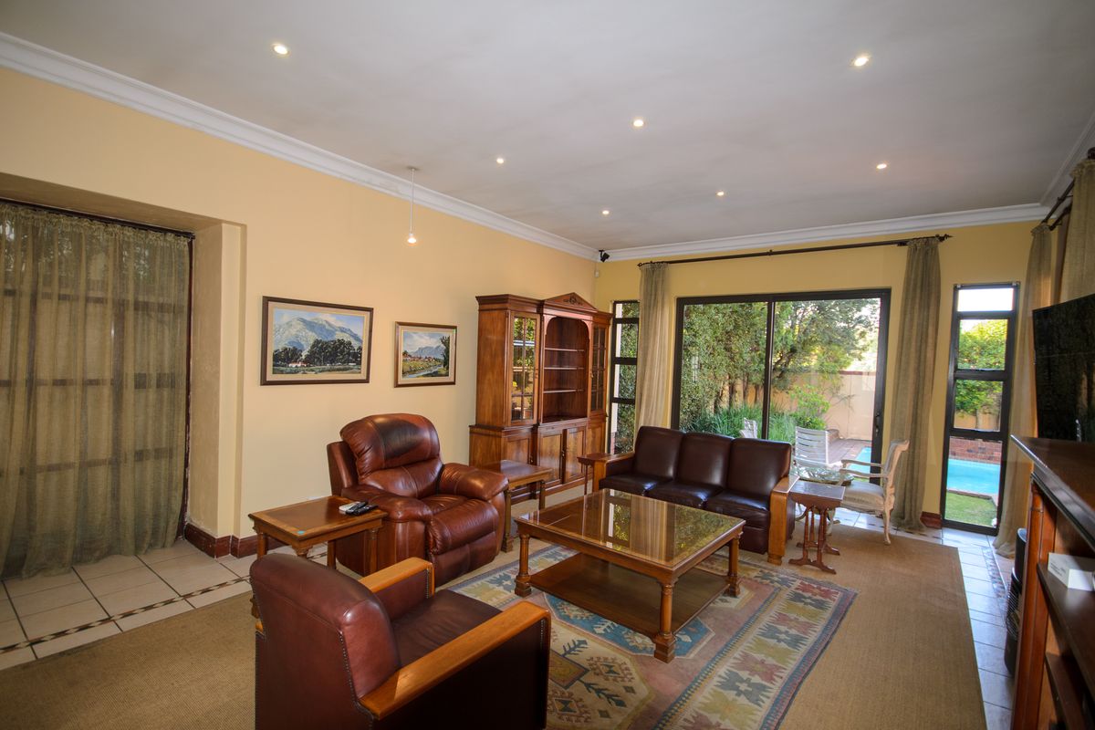 Spacious living room featuring tiled flooring, recessed downlights, and large sliding glass doors providing direct access to the outdoor pool area.