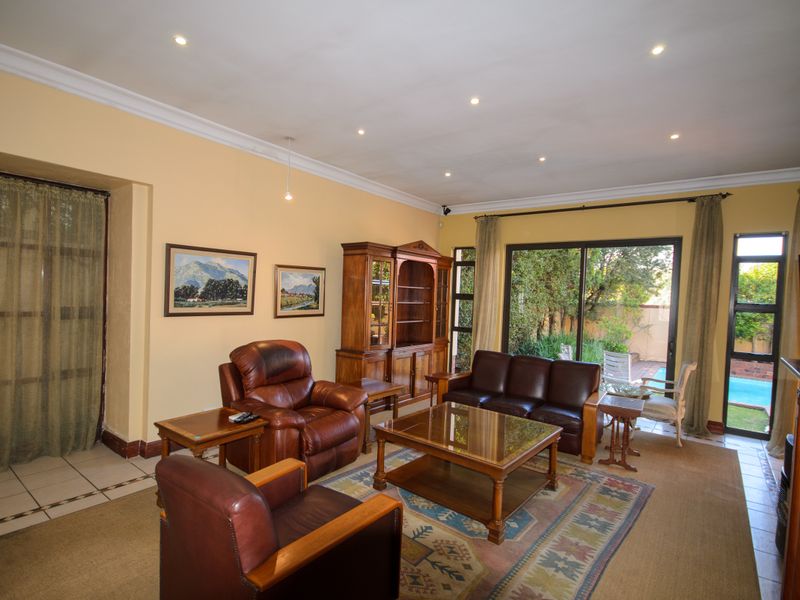 Spacious living room featuring tiled flooring, recessed downlights, and large sliding glass doors providing direct access to the outdoor pool area.