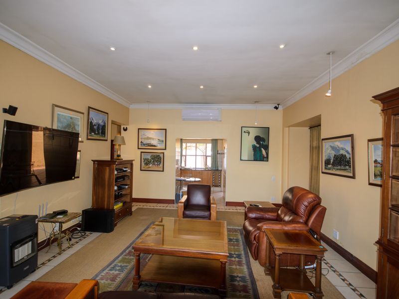 Spacious living room featuring tiled flooring, crown molding, and a wall-mounted air conditioning unit, with an open transition to the adjacent kitchen area.