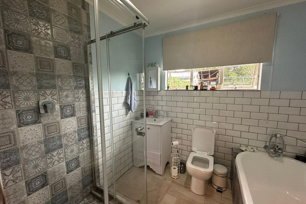 A well-maintained bathroom featuring a glass shower enclosure, vanity basin, toilet, and a freestanding bathtub with stylish subway and patterned tile finishes.