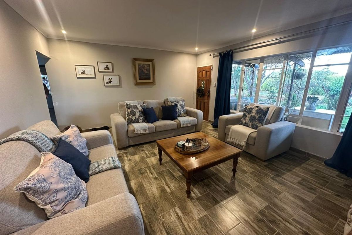 A comfortable living room featuring wood-look tiled flooring, recessed lighting, and large glass doors providing natural light and access to the outdoor area.