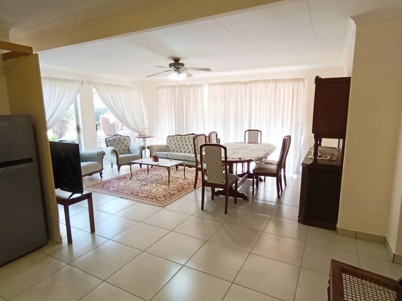 Spacious open-plan living and dining area featuring neutral tiled flooring, a ceiling fan, and large sliding glass doors providing ample natural light.