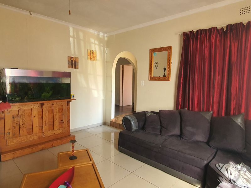 A living room featuring tiled flooring and a classic arched doorway leading to an adjacent area, providing a functional and neutral living space.
