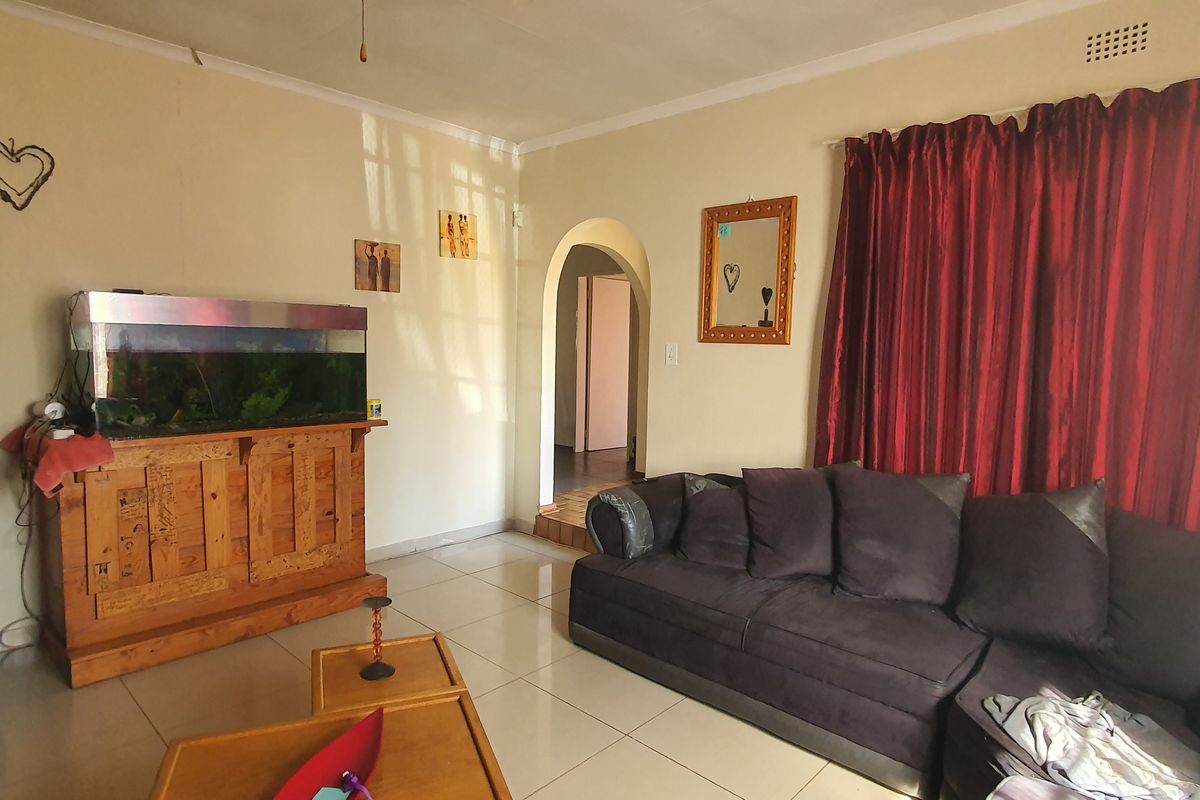 A living room featuring tiled flooring and a classic arched doorway leading to an adjacent area, providing a functional and neutral living space.