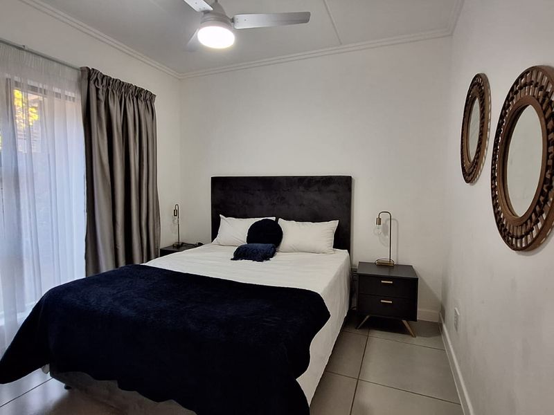 A well-maintained bedroom featuring tiled flooring, a ceiling fan, and a sliding glass door providing natural light.