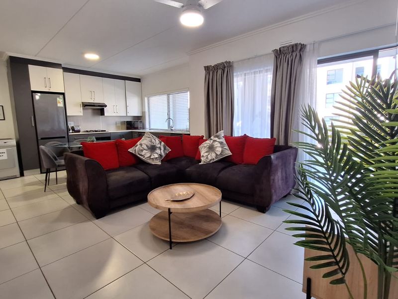 Open-plan living area featuring a modern kitchen with built-in cabinetry and tiled flooring, seamlessly connected to a bright lounge with sliding door access.