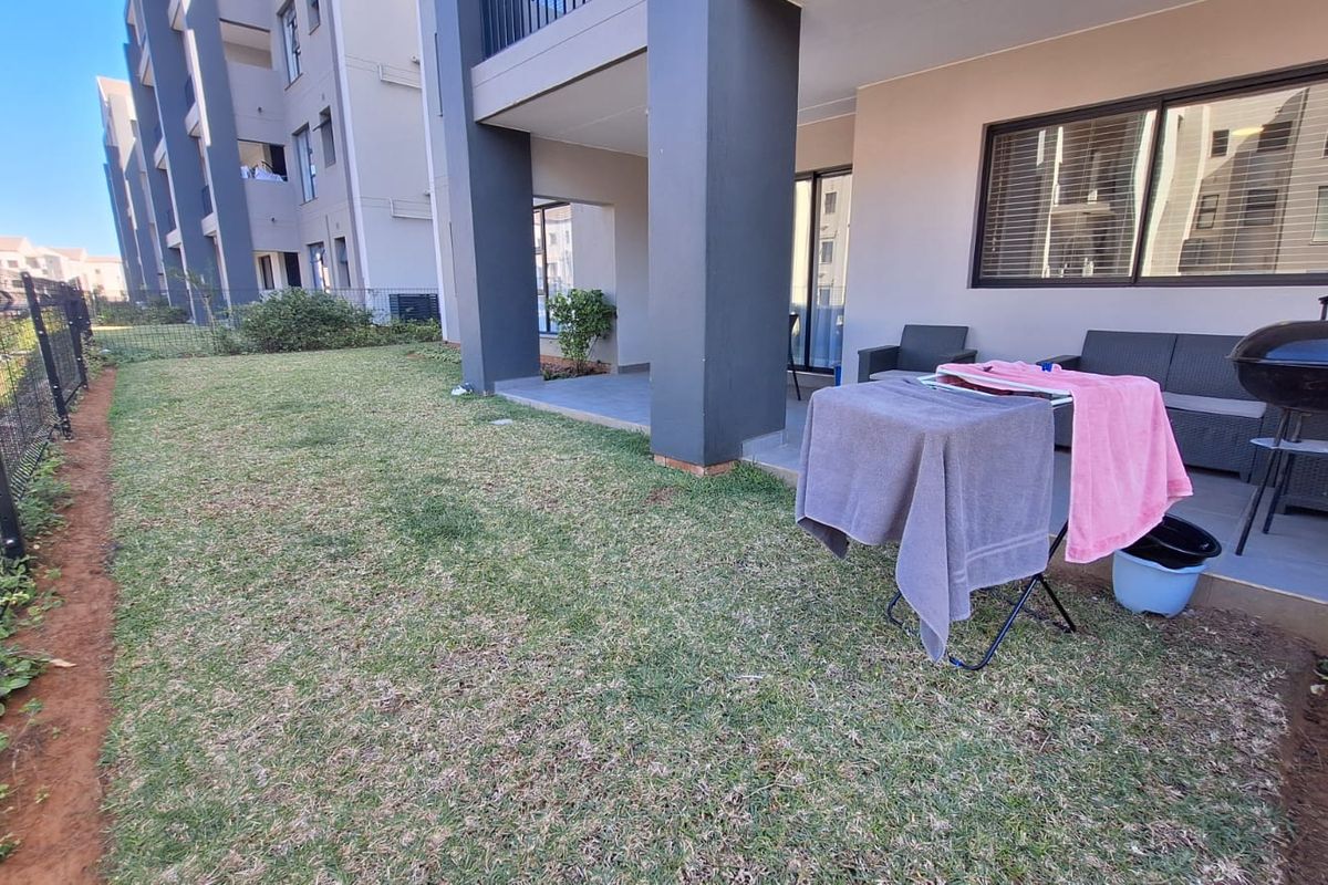 A ground-floor apartment featuring a private covered patio area and a small, fenced garden space.