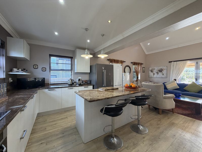 Spacious open-plan kitchen and living area featuring a central island with granite countertops, modern cabinetry, and recessed lighting throughout.