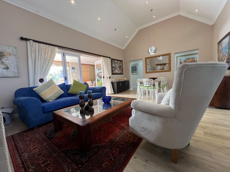 Spacious open-plan living and dining area featuring a high vaulted ceiling, recessed lighting, and large sliding doors providing seamless access to the outdoor patio.
