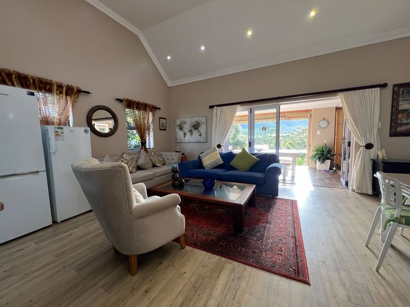 Spacious open-plan living area featuring vaulted ceilings, recessed lighting, and large sliding glass doors that provide seamless access to the outdoor patio.