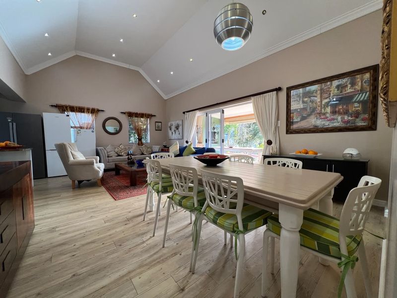 Spacious open-plan living and dining area featuring vaulted ceilings, recessed lighting, and large sliding glass doors leading to the outdoor space.
