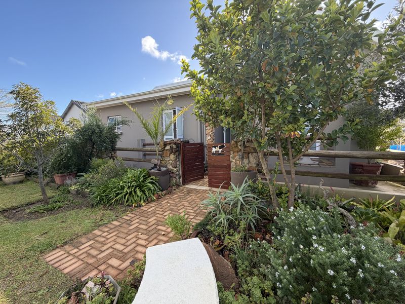 A charming front entrance featuring a brick paved path, stone masonry pillars, and timber fencing surrounded by a well-established landscaped garden.