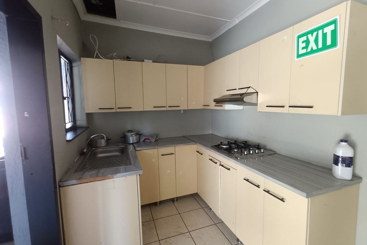 A functional kitchen featuring built-in cabinetry, laminate countertops, a gas hob, and an extractor fan, requiring some maintenance and cosmetic updates.