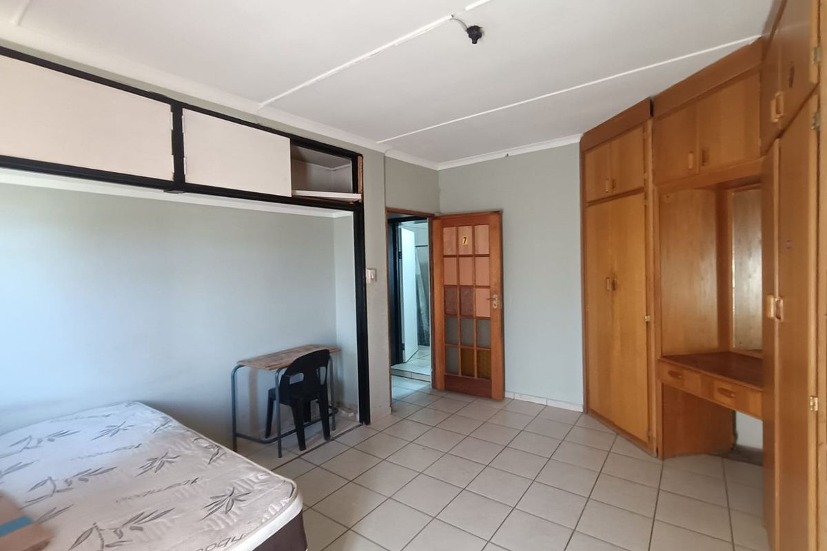 A bedroom featuring built-in wooden cupboards, overhead storage, and tiled flooring, requiring cosmetic updates to improve its overall condition.
