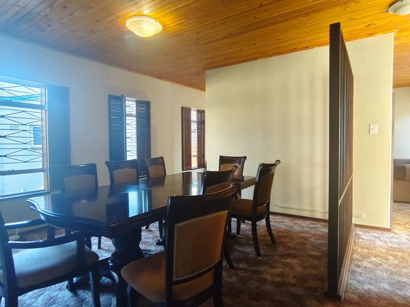 Dining room featuring a timber tongue and groove ceiling, security bars on windows, and a decorative room divider screen.