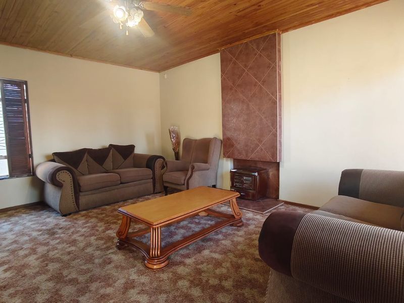 Living room featuring a timber ceiling, ceiling fan, and a tiled fireplace surround with a built-in freestanding fireplace.