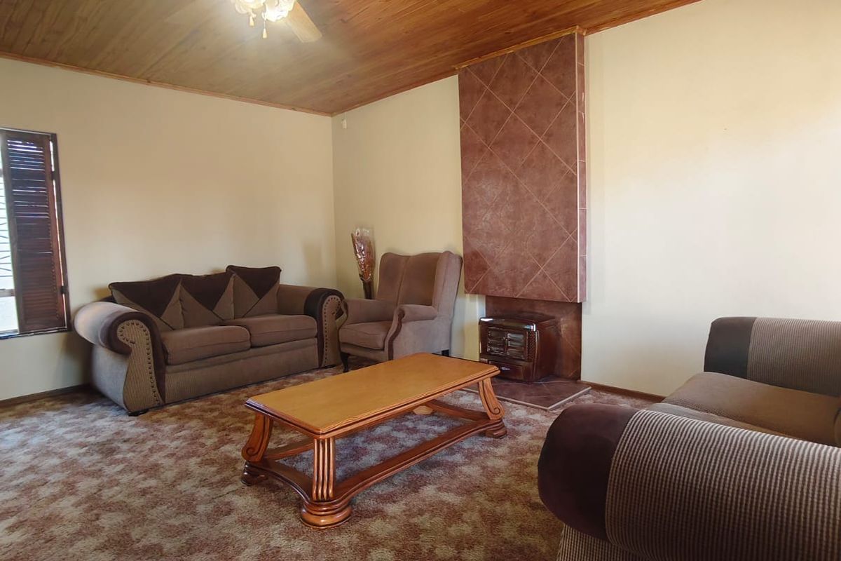 Living room featuring a timber ceiling, ceiling fan, and a tiled fireplace surround with a built-in freestanding fireplace.