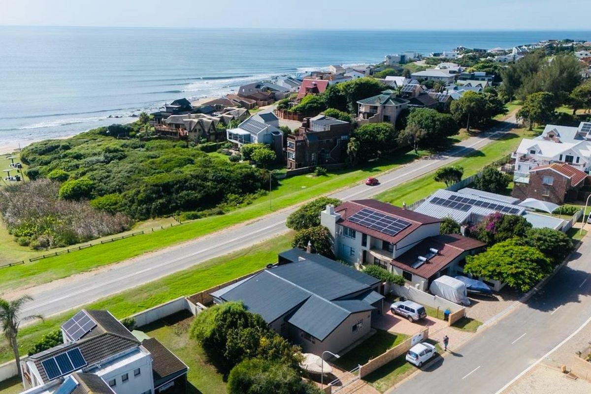 Aerial view of a coastal residential neighborhood showcasing proximity to the ocean, local road infrastructure, and properties with solar panel installations.