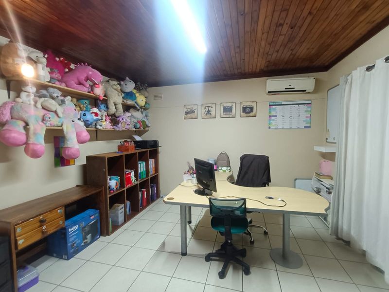 A functional home office featuring a timber tongue and groove ceiling, ceramic tiled flooring, and a wall-mounted split system air conditioner.