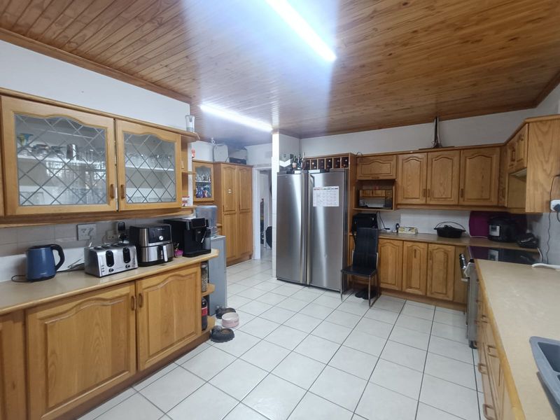A spacious kitchen featuring extensive timber cabinetry, tiled flooring, and a timber-clad ceiling, offering a functional layout with ample storage space.