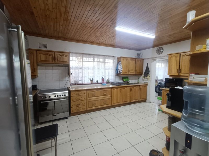 A functional kitchen featuring timber ceilings, tiled flooring, wooden cabinetry, and a freestanding oven, offering a classic layout with potential for modern updates.
