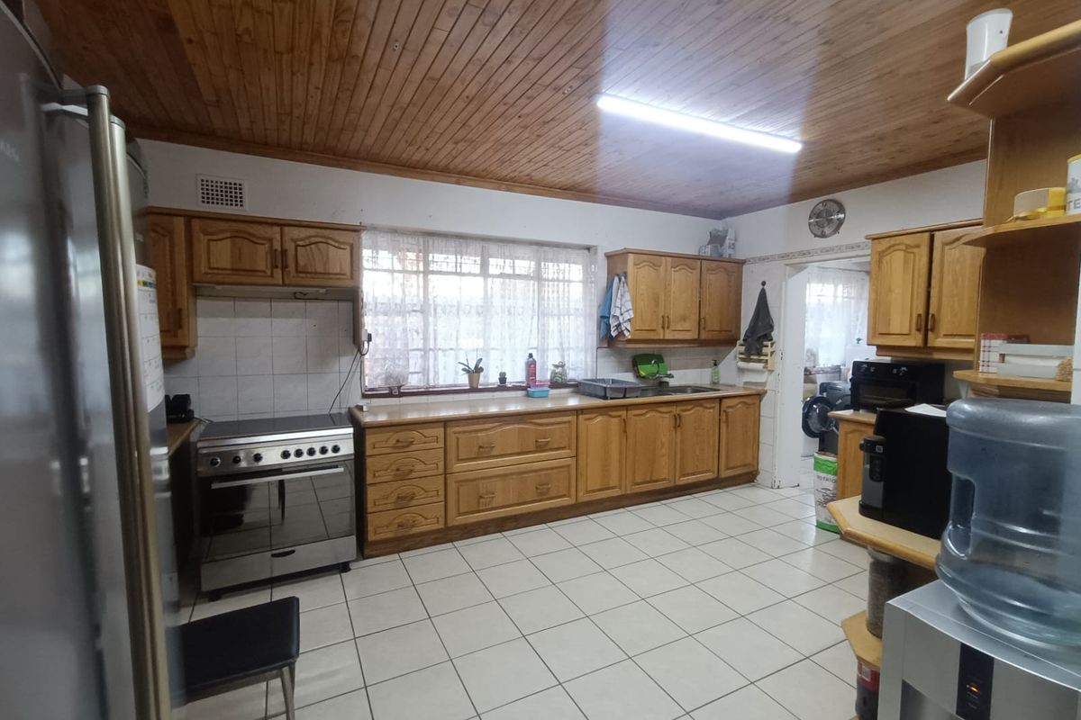 A functional kitchen featuring timber ceilings, tiled flooring, wooden cabinetry, and a freestanding oven, offering a classic layout with potential for modern updates.
