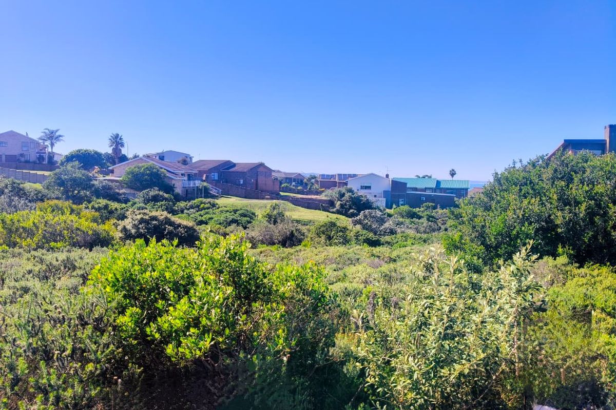 A scenic view overlooking a natural landscape with surrounding residential properties in the distance under a clear blue sky.