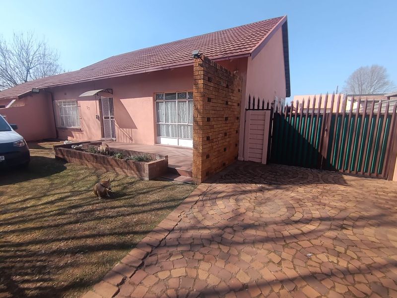 Front exterior view of a single-story house featuring a paved driveway, brick feature wall, and a small front garden area with a planter box.