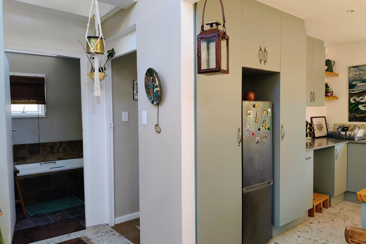 A functional kitchen area featuring sage green built-in cabinetry, terrazzo flooring, and a seamless transition to an adjacent bathroom space.