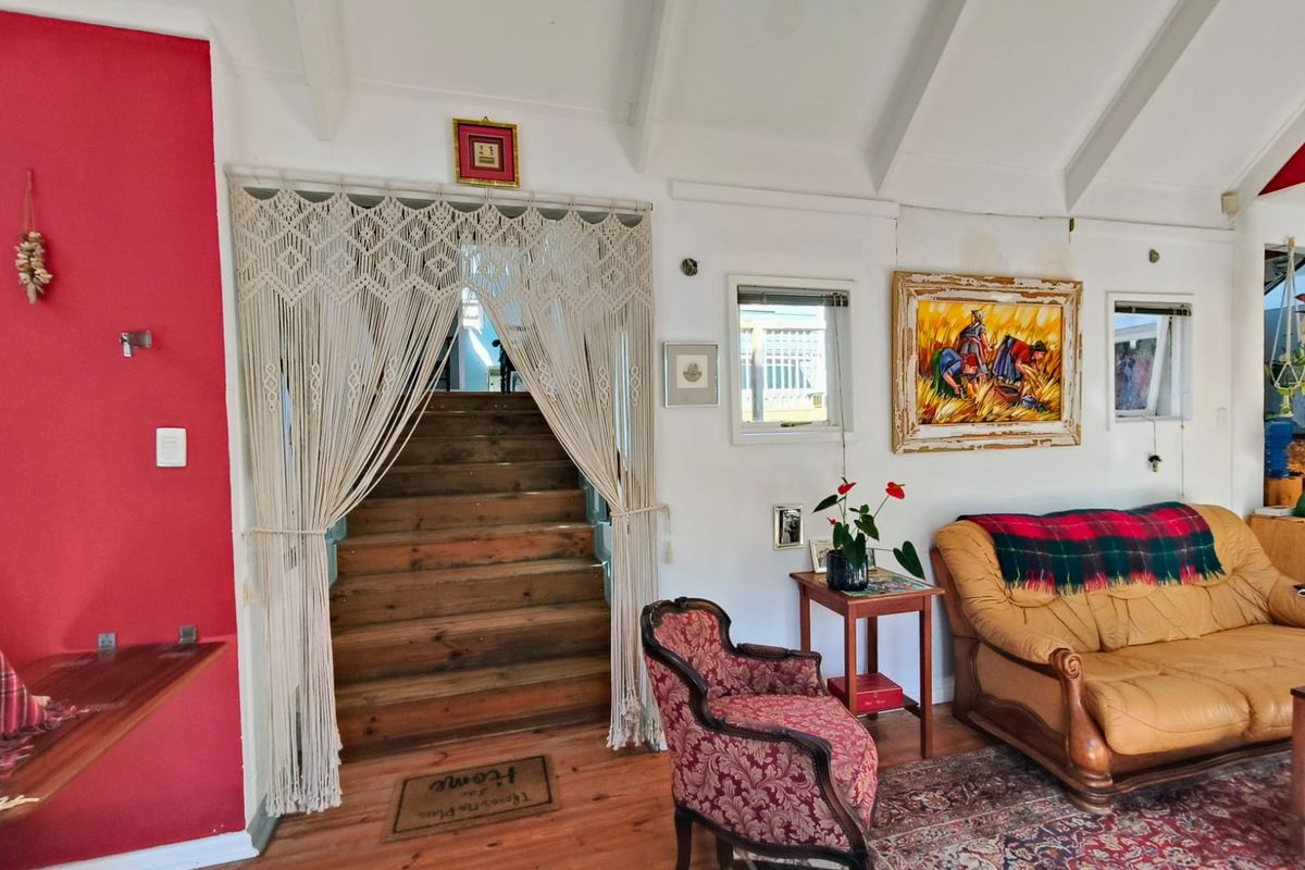 Living room featuring exposed timber ceiling beams, timber flooring, and a wooden staircase leading to an upper level.