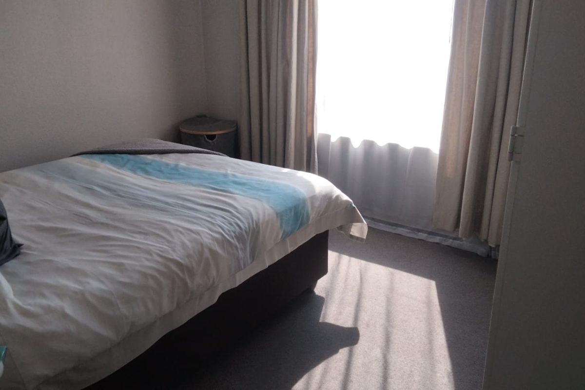 A standard bedroom featuring carpeted flooring and window curtains, providing a functional and private living space.
