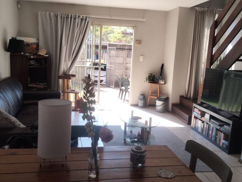 Open plan living area featuring tiled flooring, a staircase, and direct access to an outdoor patio area.