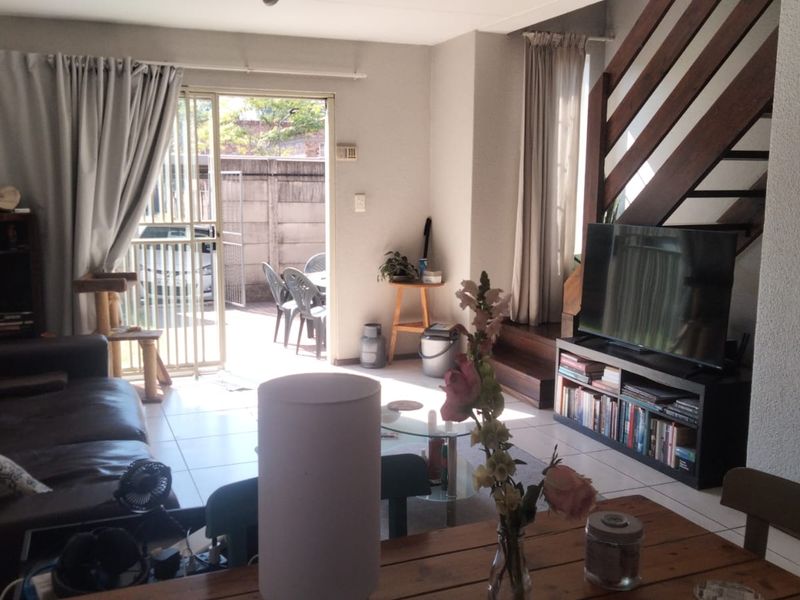 Open-plan living area featuring tiled flooring, a staircase with a wooden balustrade, and a sliding glass door providing access to the outdoor patio.
