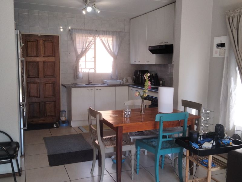 Open-plan kitchen and dining area featuring tiled flooring, white cabinetry, and a functional layout suitable for modern living.