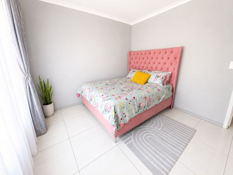 A bright and well-maintained bedroom featuring neutral wall tones, tiled flooring, and coved ceiling details.