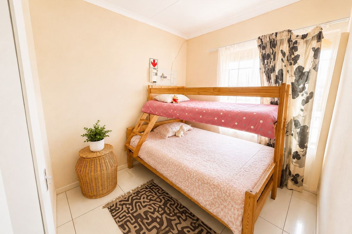 A compact bedroom featuring tiled flooring and a neutral wall finish, equipped with a wall-mounted electrical distribution board.