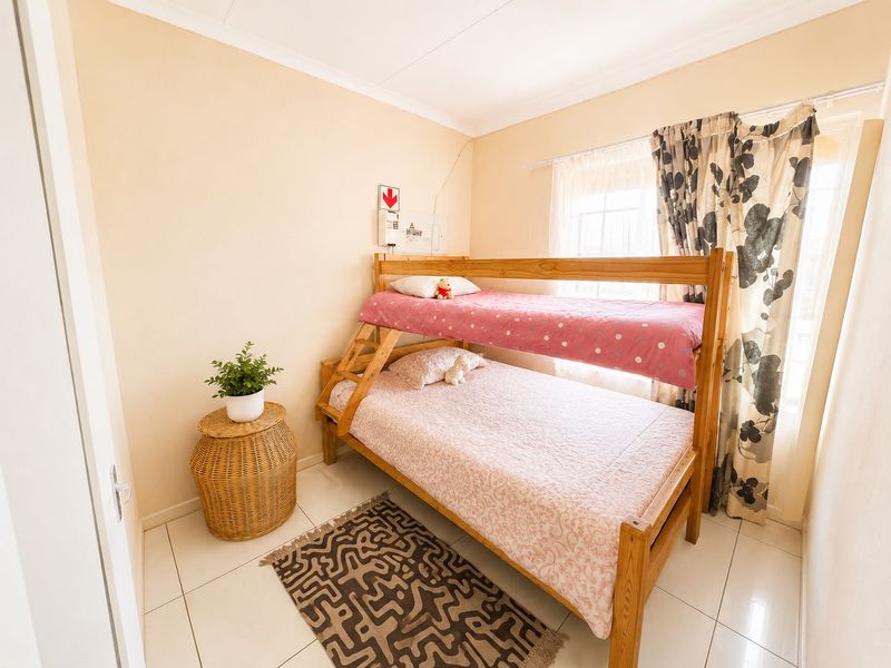 A compact bedroom featuring tiled flooring and a neutral wall finish, equipped with a wall-mounted electrical distribution board.