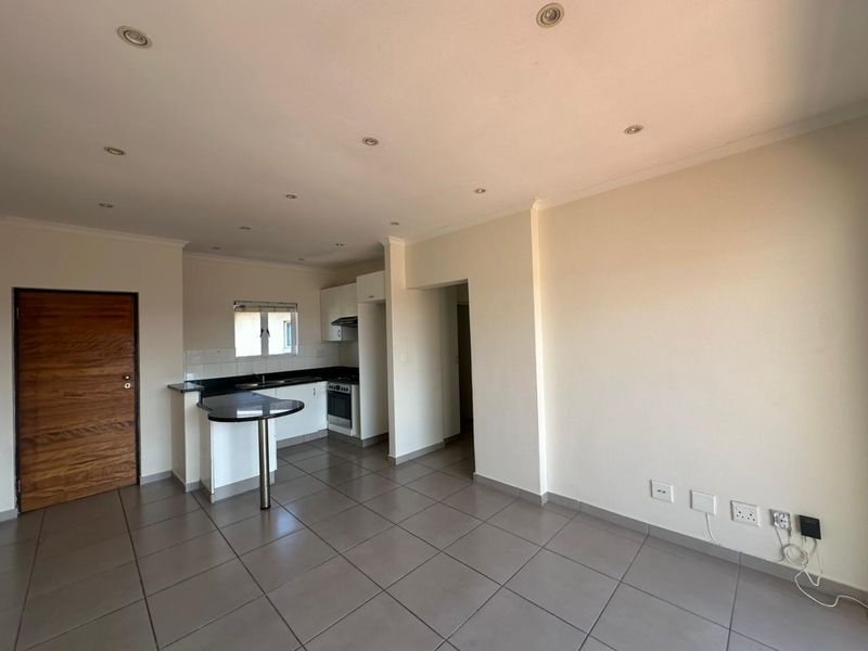 Open-plan living area featuring tiled floors, recessed lighting, and a compact kitchen with granite countertops, breakfast bar, and built-in oven.