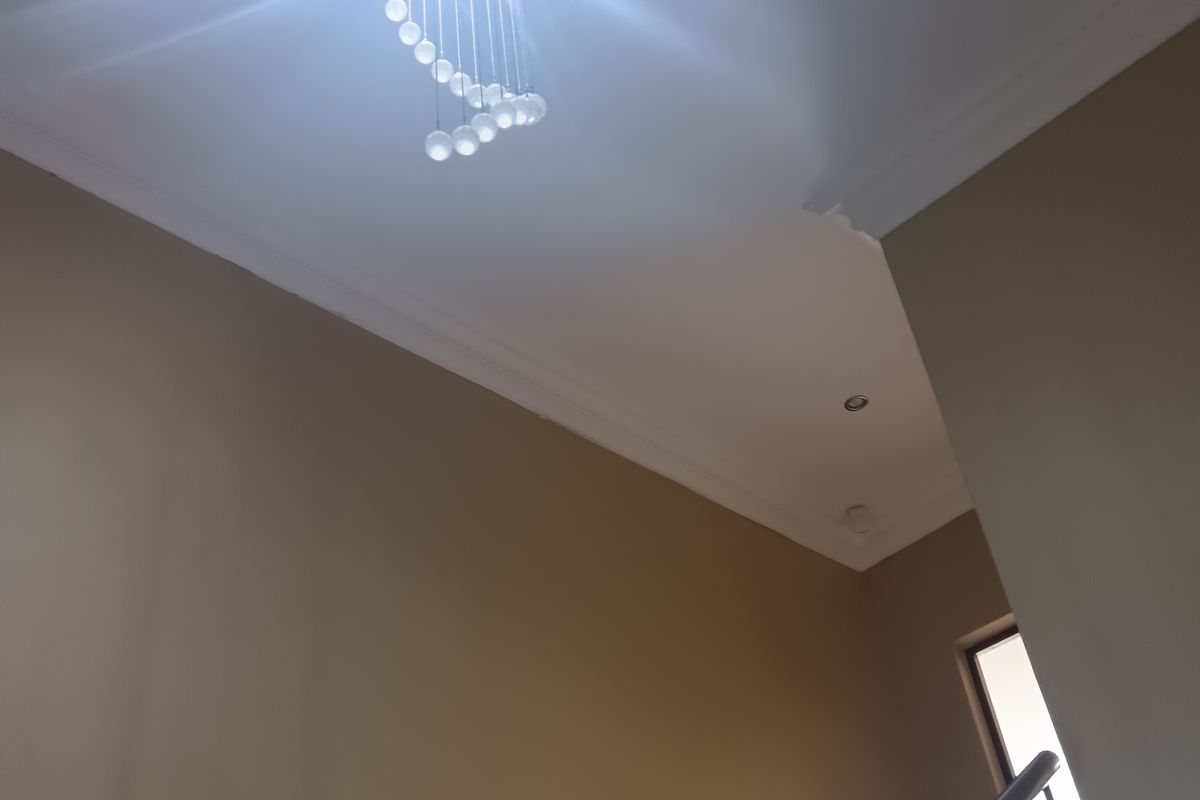 A bright hallway featuring a modern stainless steel balustrade staircase and a decorative pendant light fixture.