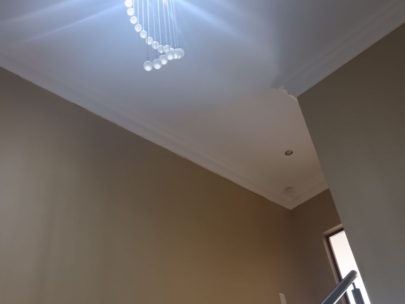 A bright hallway featuring a modern stainless steel balustrade staircase and a decorative pendant light fixture.