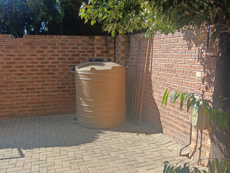 A private rear courtyard area featuring paved flooring, a brick boundary wall, and a functional water storage tank.