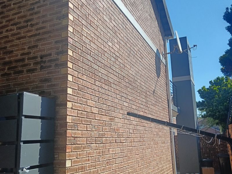 Side view of the townhouse featuring face brick exterior walls, paved ground area, and external chimney stack.