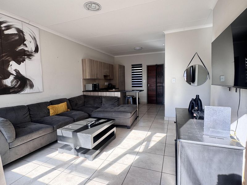 Open-plan living area featuring tiled flooring, a breakfast counter, and integrated kitchen cabinetry, creating a functional and connected living space.